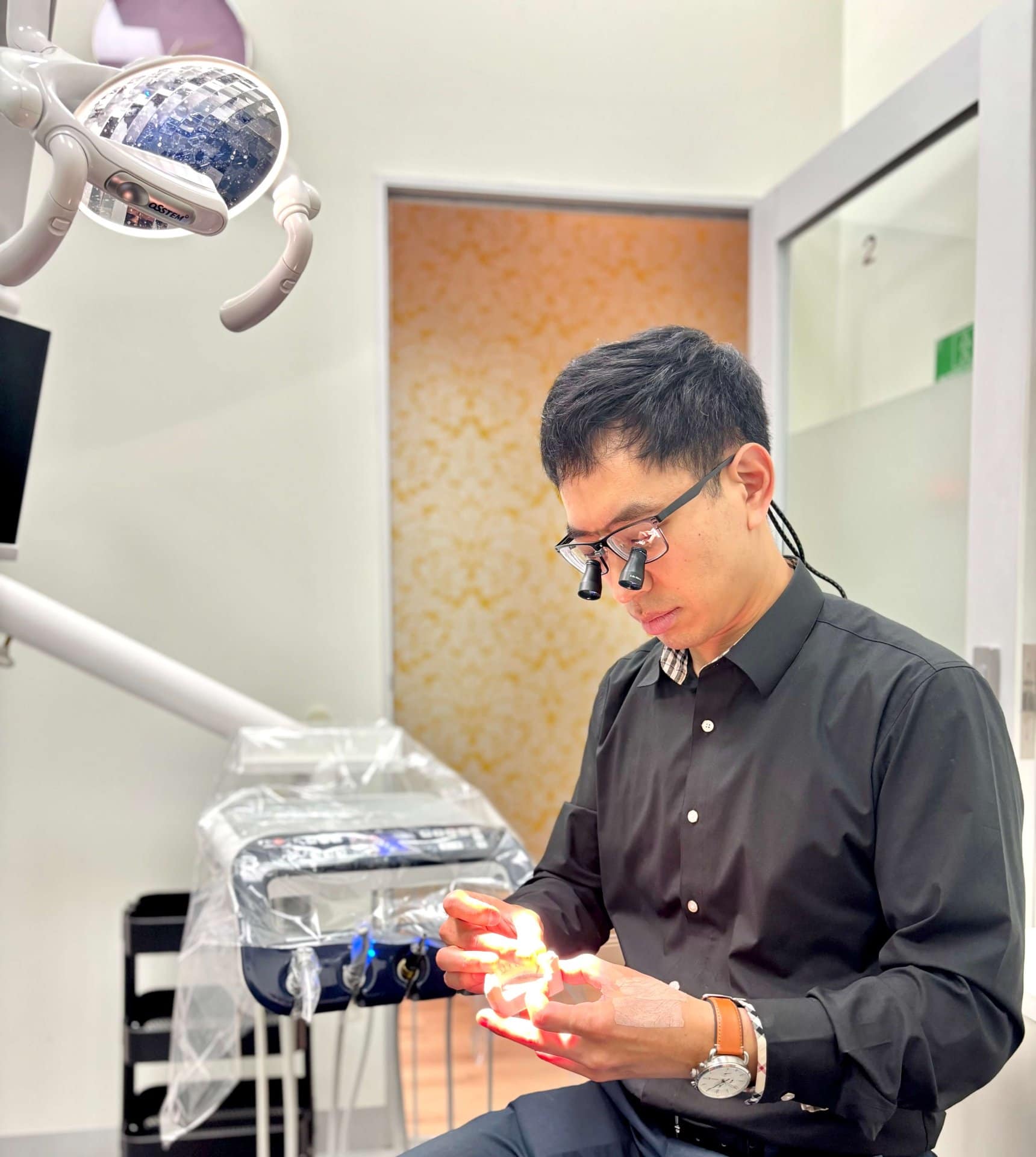 Dr Jun Kim examining a tooth model in Prahran