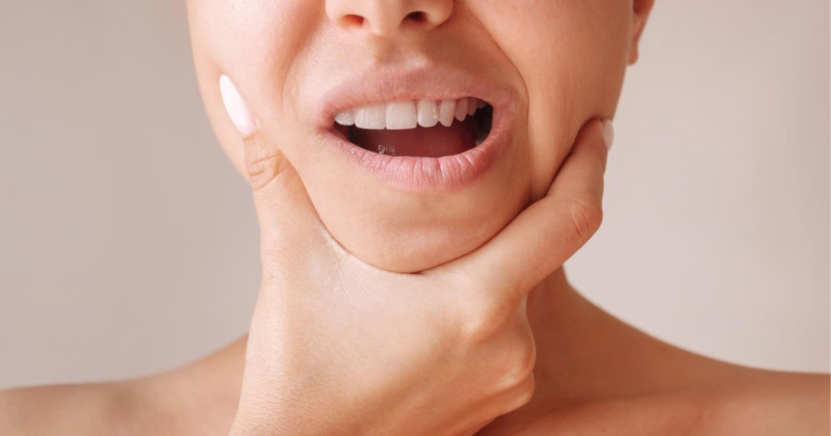 woman holding her jaw due to discomfort relevant to jaw tension from teeth grinding in Prahran